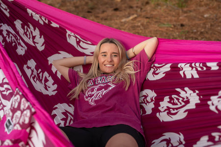 Woman wearing NRL merch laying in Manly Sea Eagle NRL Nakie Hammock