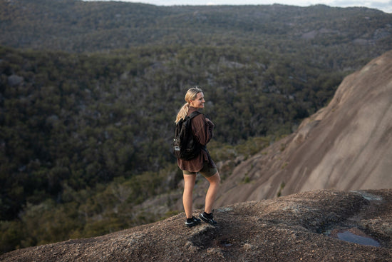 Person hiking with a Nakie foldable backpack overlooking a mountain landscape.