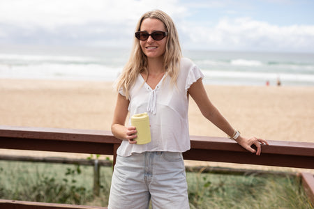 Woman with a Daisy Yellow Cooler & Coffee Cup at the beach