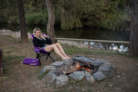 Mulberry Purple camping chair and carry bag by a campfire