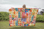 Retro Shores patchwork puffy blanket with colorful geometric and tropical print blocks, displayed outdoors by ocean. preview #6