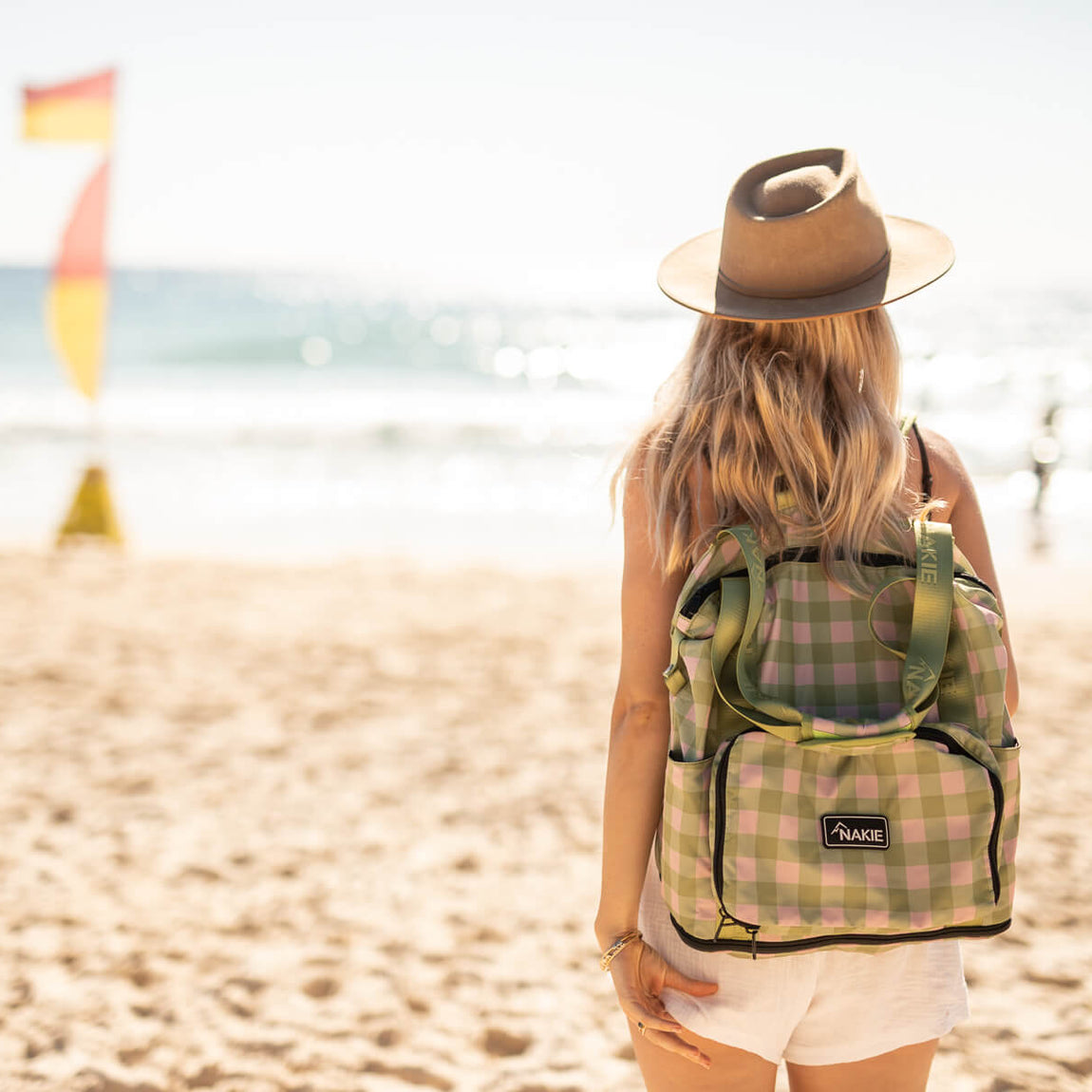 Strawberry Fields recycled tote bag in pink and green gingham, worn on shoulder at beach