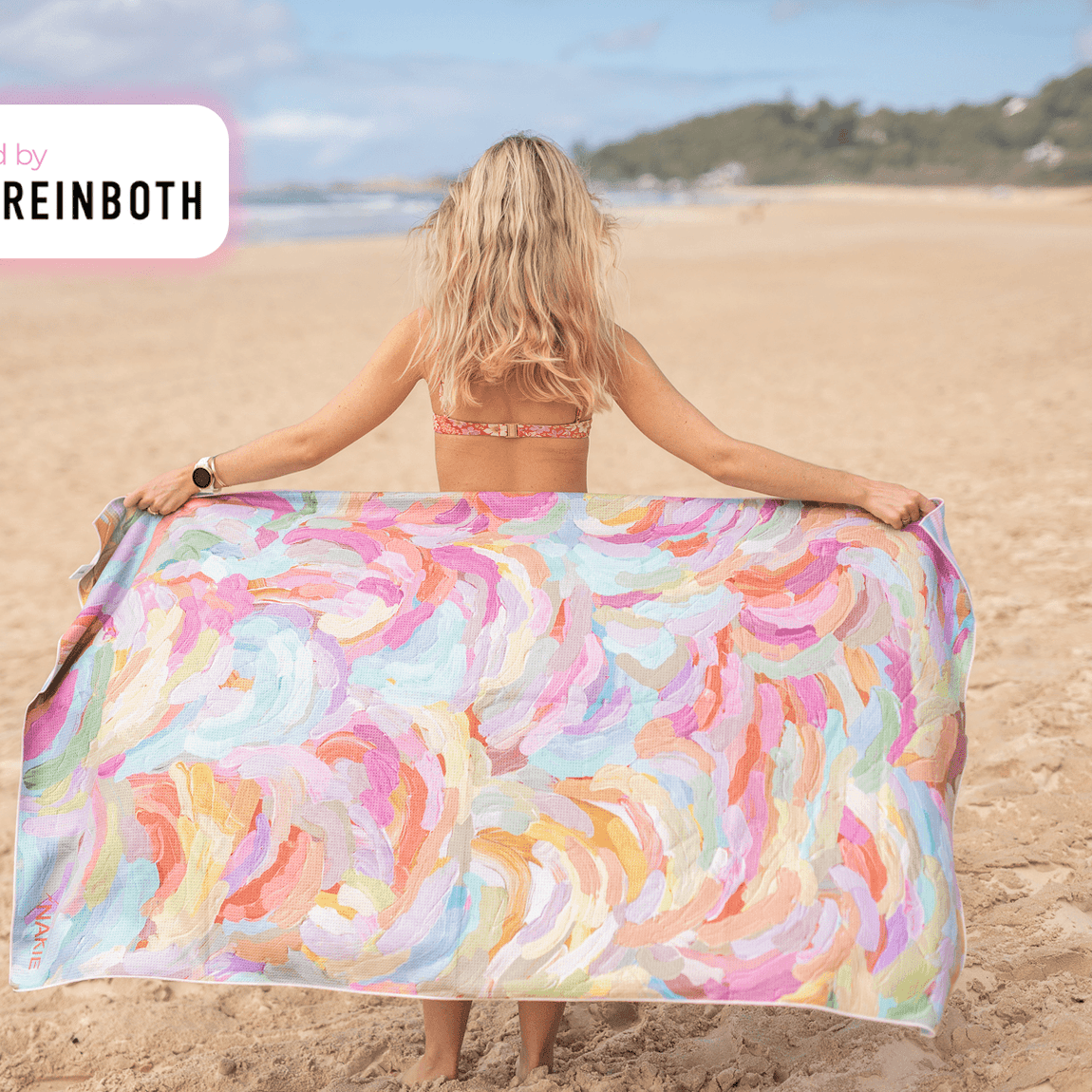 Recycled sand-free beach towel with multicolor abstract brushstroke pattern, held open on beach