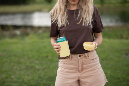 Daisy Yellow Cooler & Coffee Cup with a can inside and the lid in hand