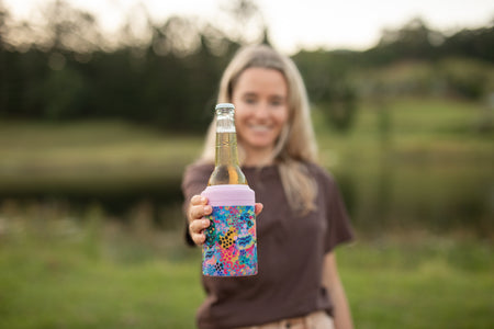 Kasey Rainbow Cooler & Coffee Cup holding a beer bottle outdoors