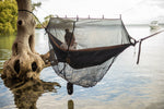 A woman sitting inside Nakie's Bug Net on a hammock, set up in a mangrove forest, enjoying protected and insect-free relaxation amidst the unique coastal environment. preview #10