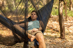 A man lying down on a hammock in a campsite, looking at Nakie's Bug Net, enjoying the comfort and protection of the setup. preview #16