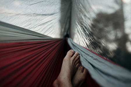 Feet visible from inside Nakie's Bug Net, as the person relaxes in a hammock, enjoying protection from insects for a comfortable outdoor experience.